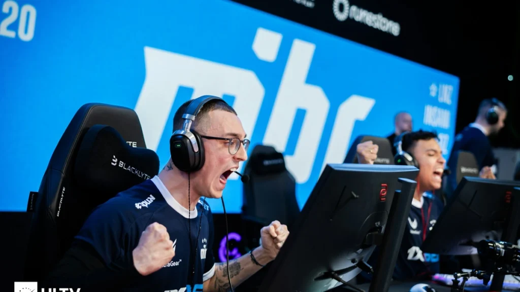 NQZ do MIBR, comemora round em partida de CS2 com o logo do time no telão ao fundo